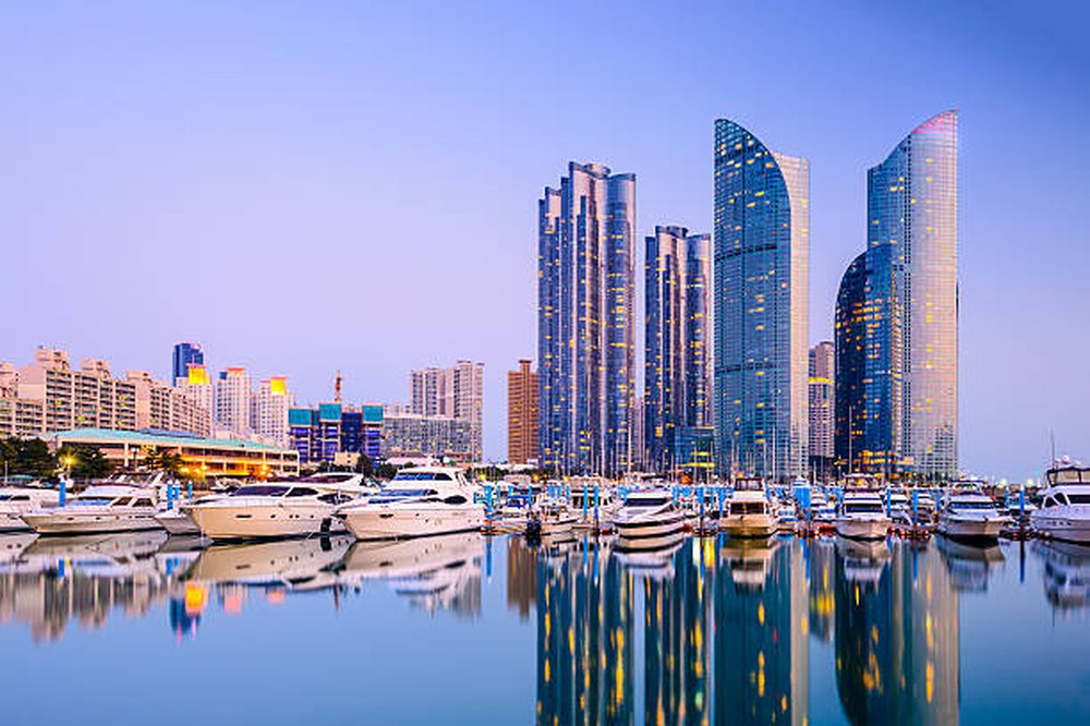 Jachthaven en skyline van Busan in de avondschemering