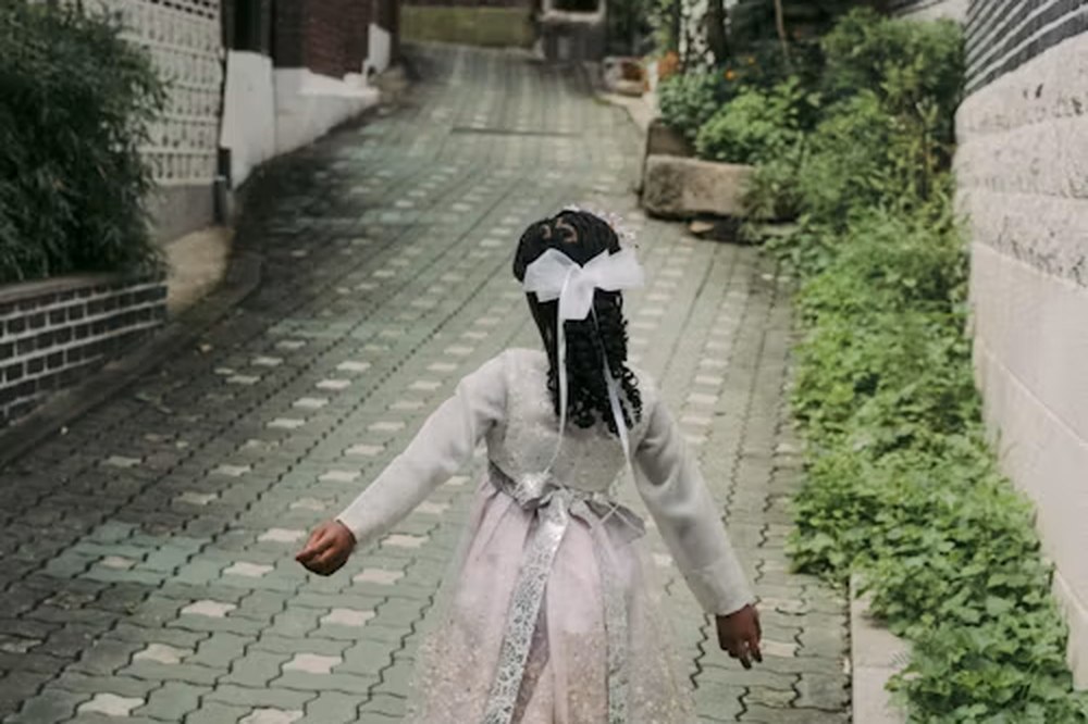 Kind in hanbok loopt door een steegje in een hanokdorp